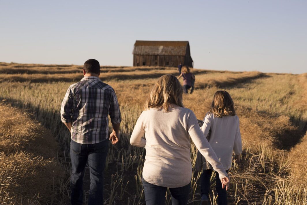 Famille qui se dirige vers une grange en plein champ